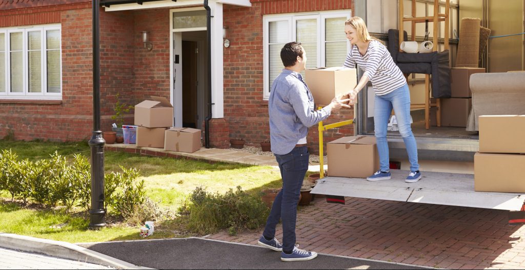 Couple Unpacking Moving In Boxes From Removal Truck